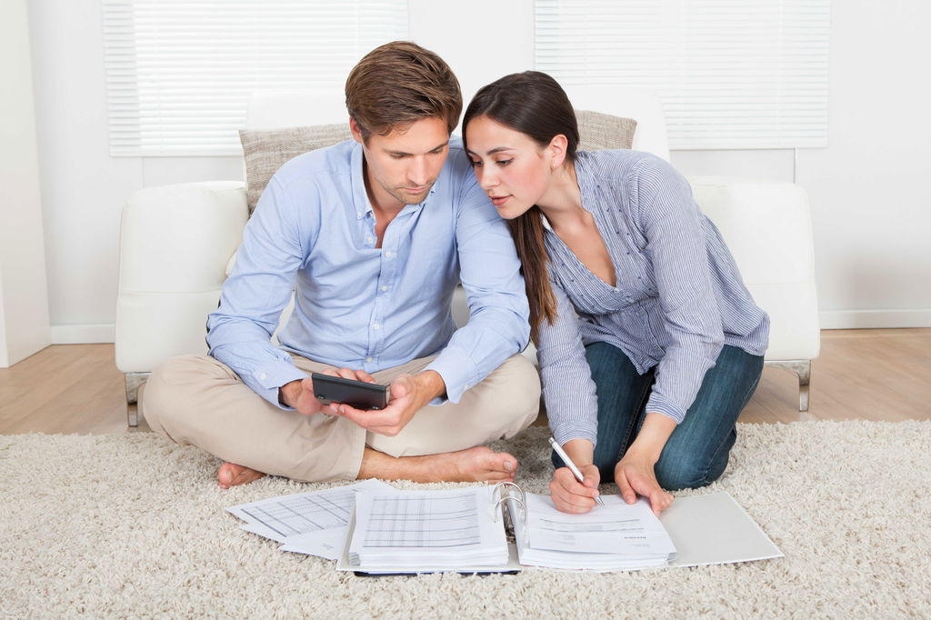 גבר ואשה יושבים על שטיח ומולם ניירות  ומחשבון