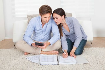 גבר ואשה יושבים על שטיח ומולם ניירות  ומחשבון