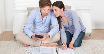 גבר ואשה יושבים על שטיח ומולם ניירות  ומחשבון