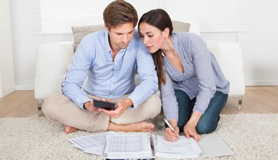 גבר ואשה יושבים על שטיח ומולם ניירות  ומחשבון
